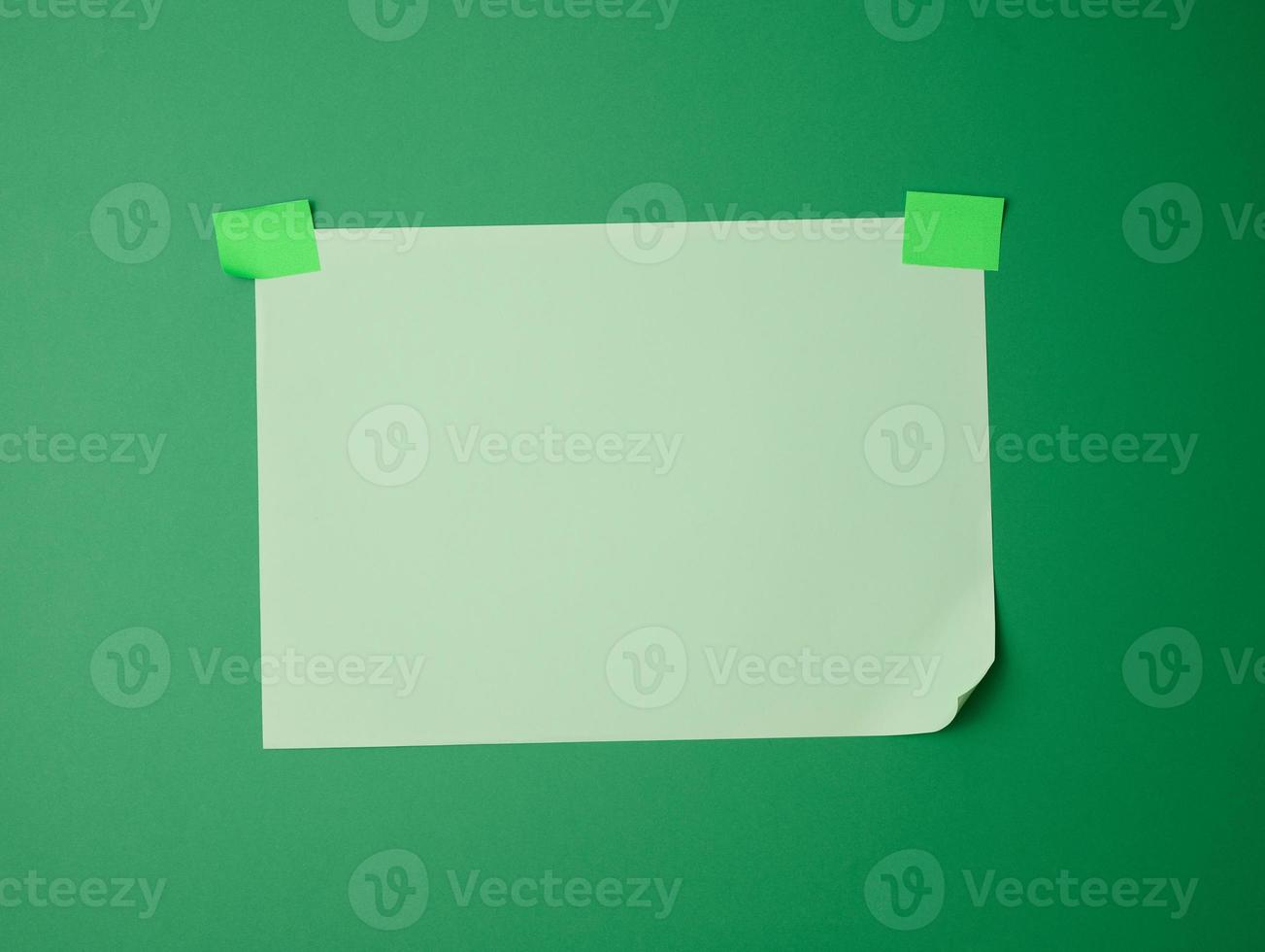 rectangular blank green sheet of paper glued with green sticky paper on green background photo