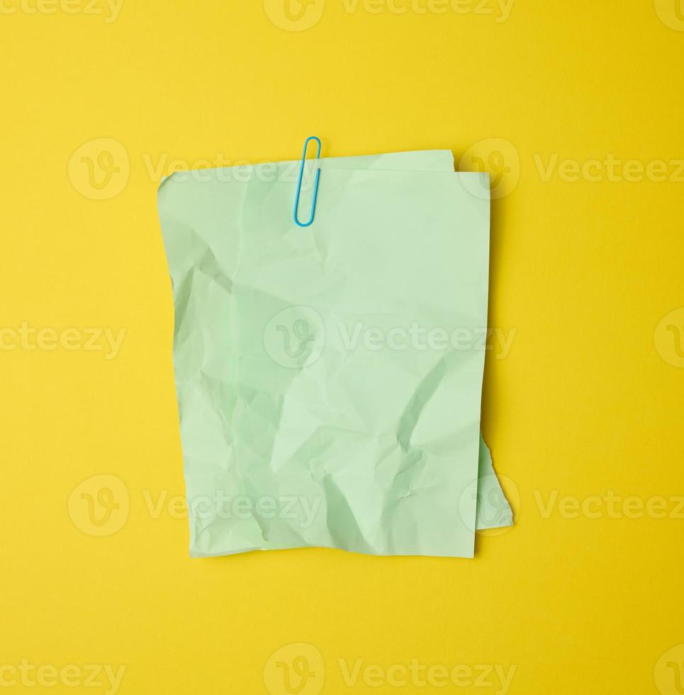 rectangular crumpled blank green sheet of paper on yellow background photo