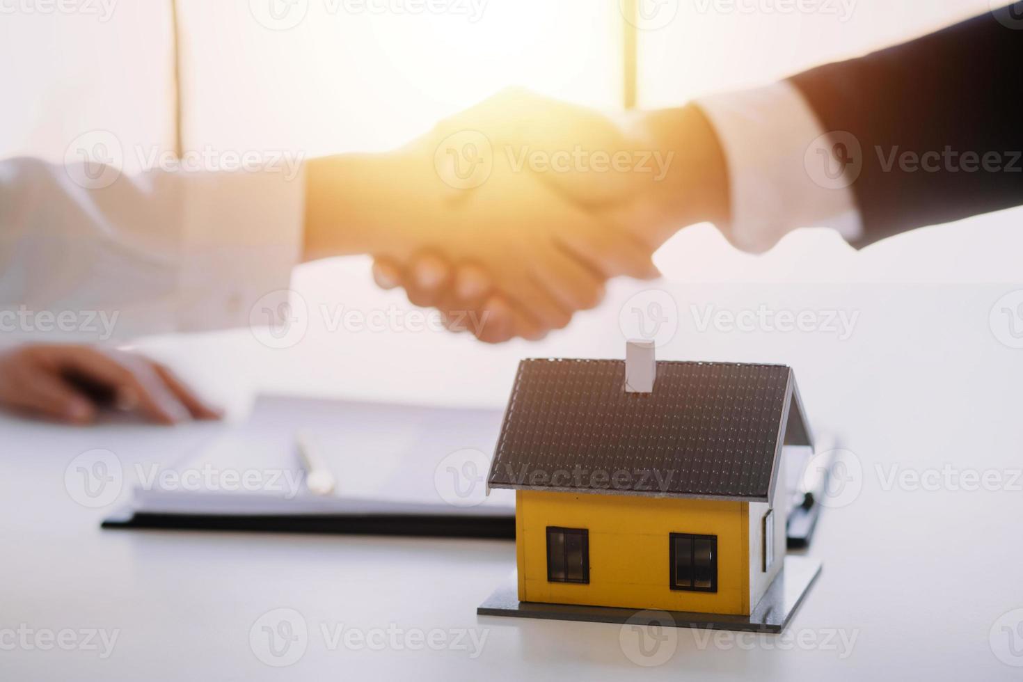 agente de corretaje de bienes raíces entrega una muestra de una casa modelo al cliente, contrato de préstamo hipotecario que arrienda y compra y vende casa y contrata el concepto de préstamo hipotecario de seguro de hogar foto