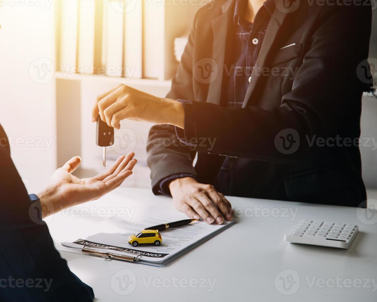 Hand holding car keys and car rental concept A close-up view of the agent, giving the customer the car keys after signing the lease, rental form and car name. photo