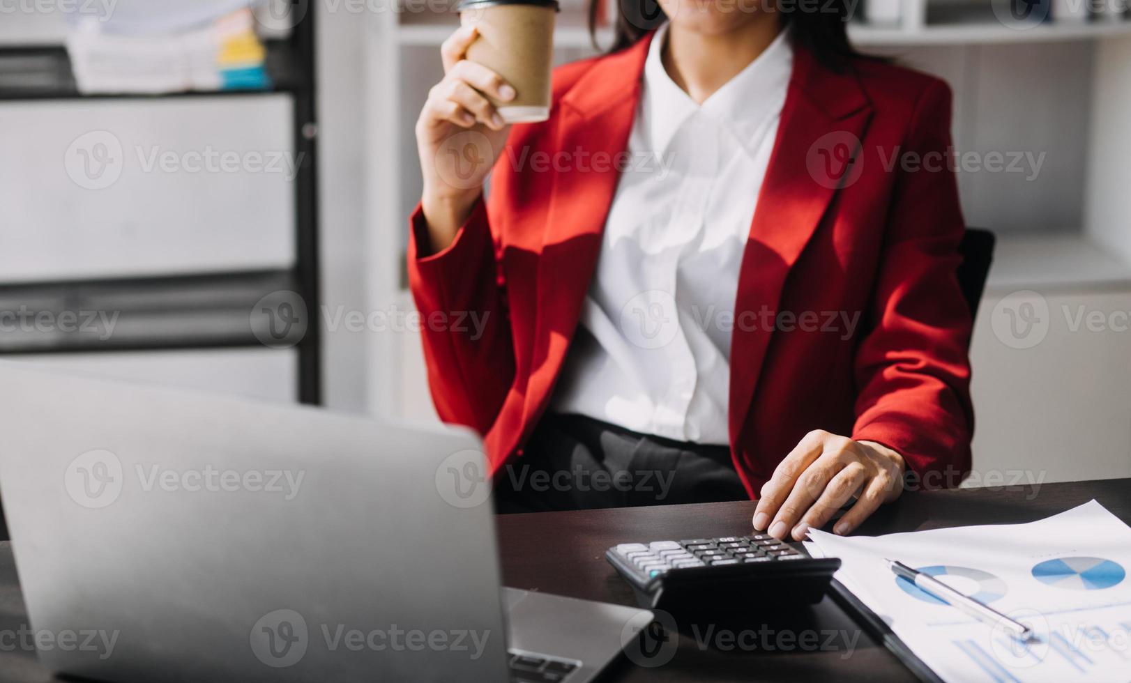Asian Business woman using calculator and laptop for doing math finance on an office desk, tax, report, accounting, statistics, and analytical research concept photo