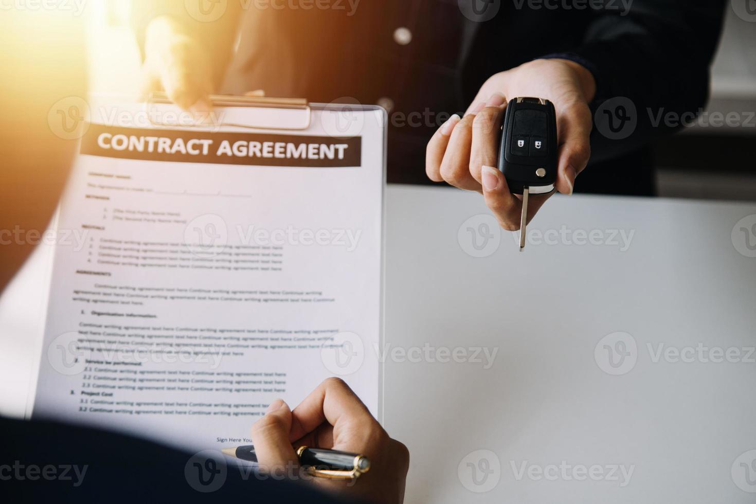 Hand holding car keys and car rental concept A close-up view of the agent, giving the customer the car keys after signing the lease, rental form and car name. photo