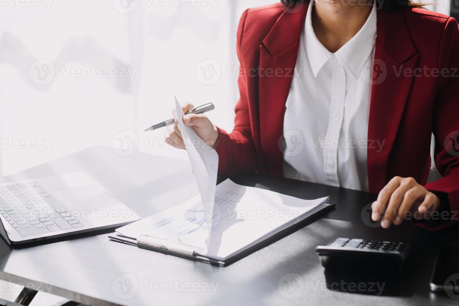 Asian Business woman using calculator and laptop for doing math finance on an office desk, tax, report, accounting, statistics, and analytical research concept photo