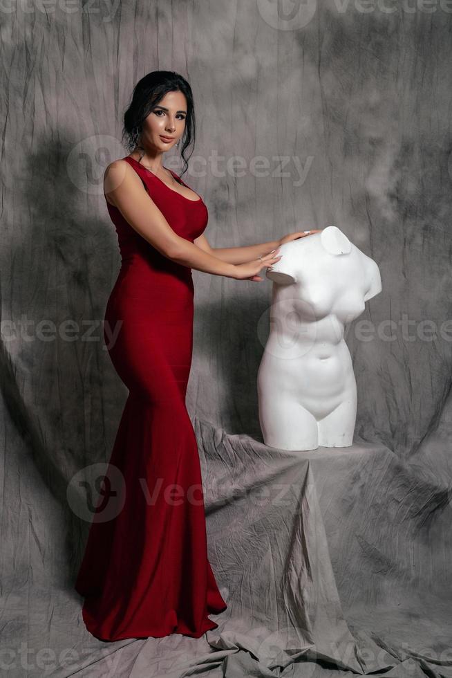 girl in a red evening dress on a gray background photo
