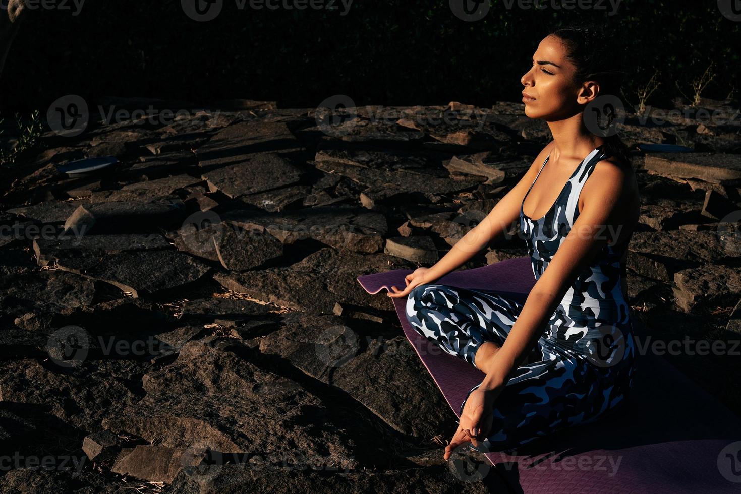 niña medita en naturaleza se sienta con cerrado ojos en piedras foto