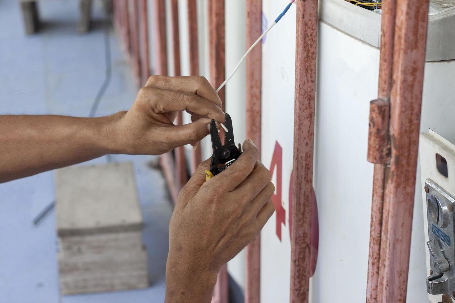 The mechanic's hand holds the pliers stripping the wires while repairing the electrical appliances. photo