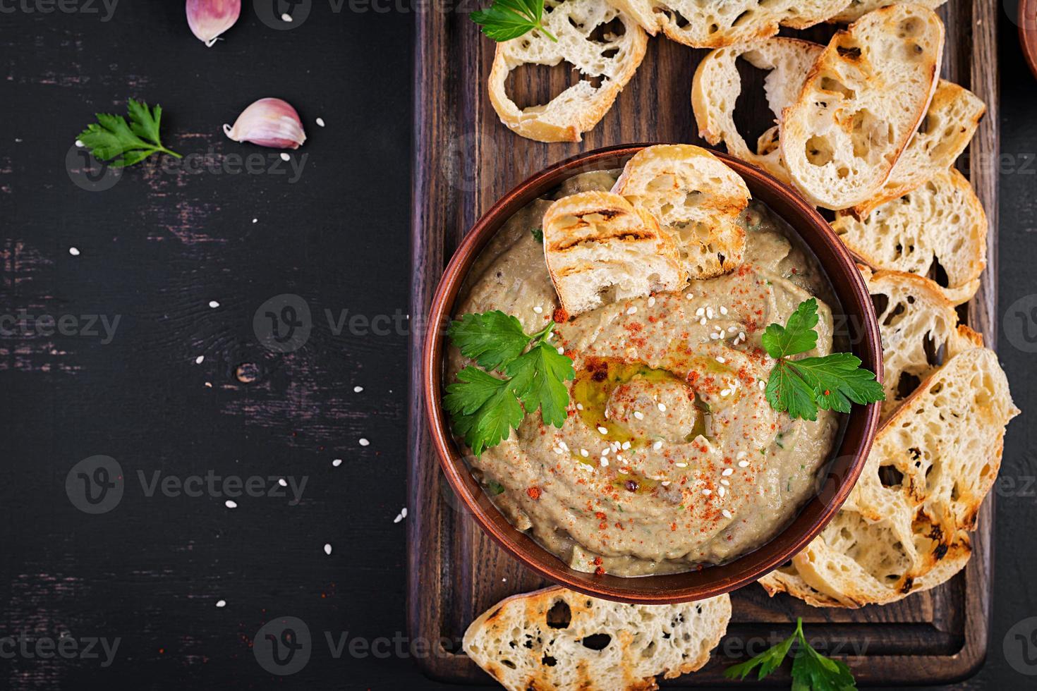 Baba ghanoush vegan hummus from eggplant with seasoning, parsley and toasts. Baba ganoush. Middle Eastern cuisine. Top view, overhead photo