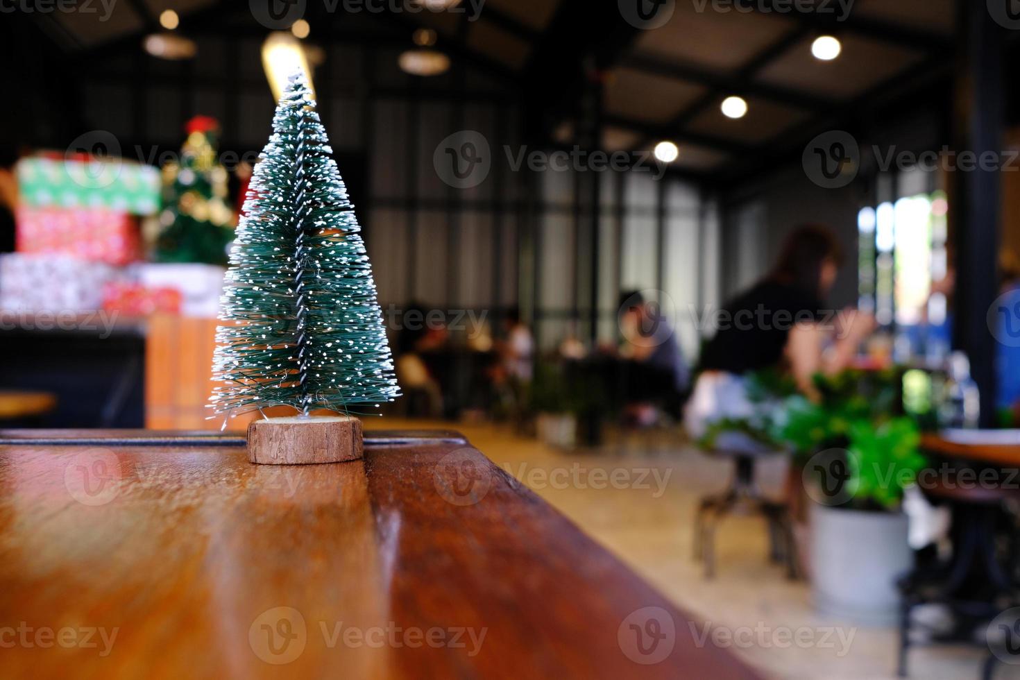 Artificial Christmas Tree on Wooden Table in Coffee Shop Background. photo