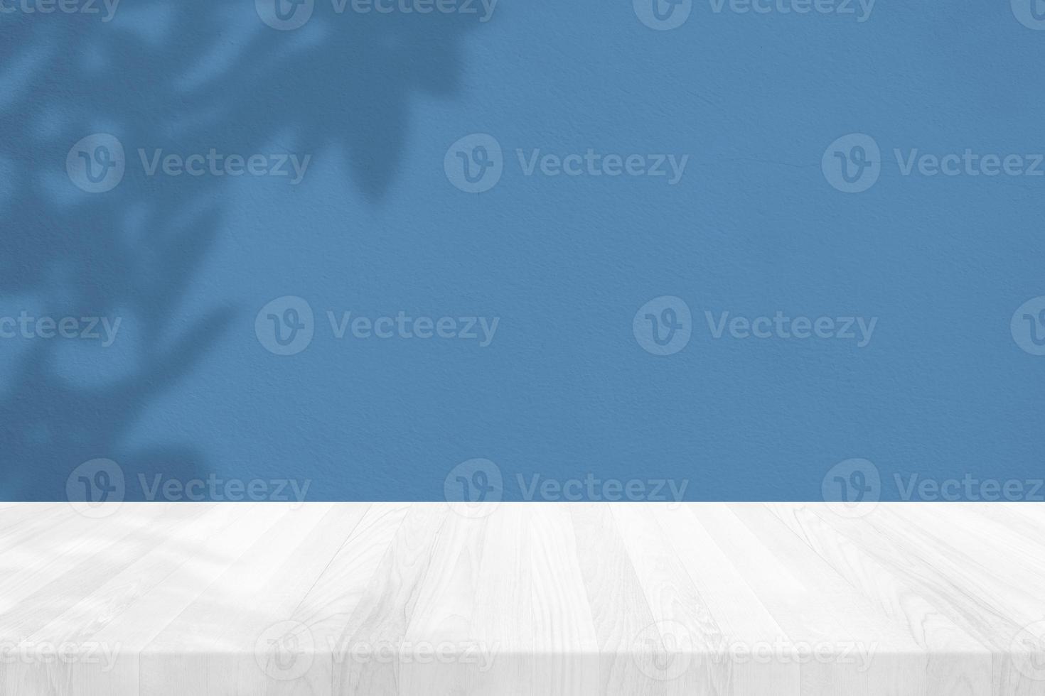 Wood Table with Leaves Shadow on Stucco Wall Texture Background in Tranquil Blue Tone, Suitable for Product Presentation Backdrop, Display, and Mock up. photo