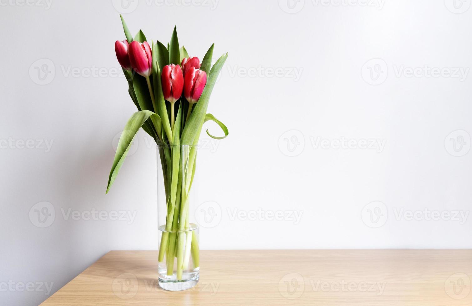 Pink tulip flowers in transparent glass vase on wooden table, early spring romantic holiday gift concept with copy space, Mother's day design, selective focus, home interior decor photo