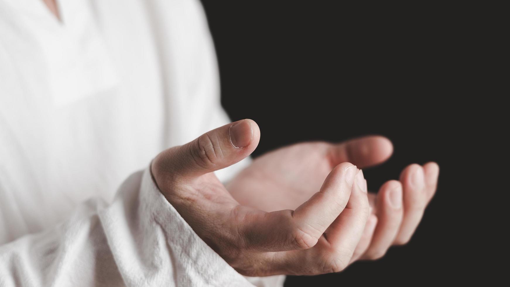An adult whose hand is prayed on the dark background.Respect for belief in religion and God. front view. peace concept. photo