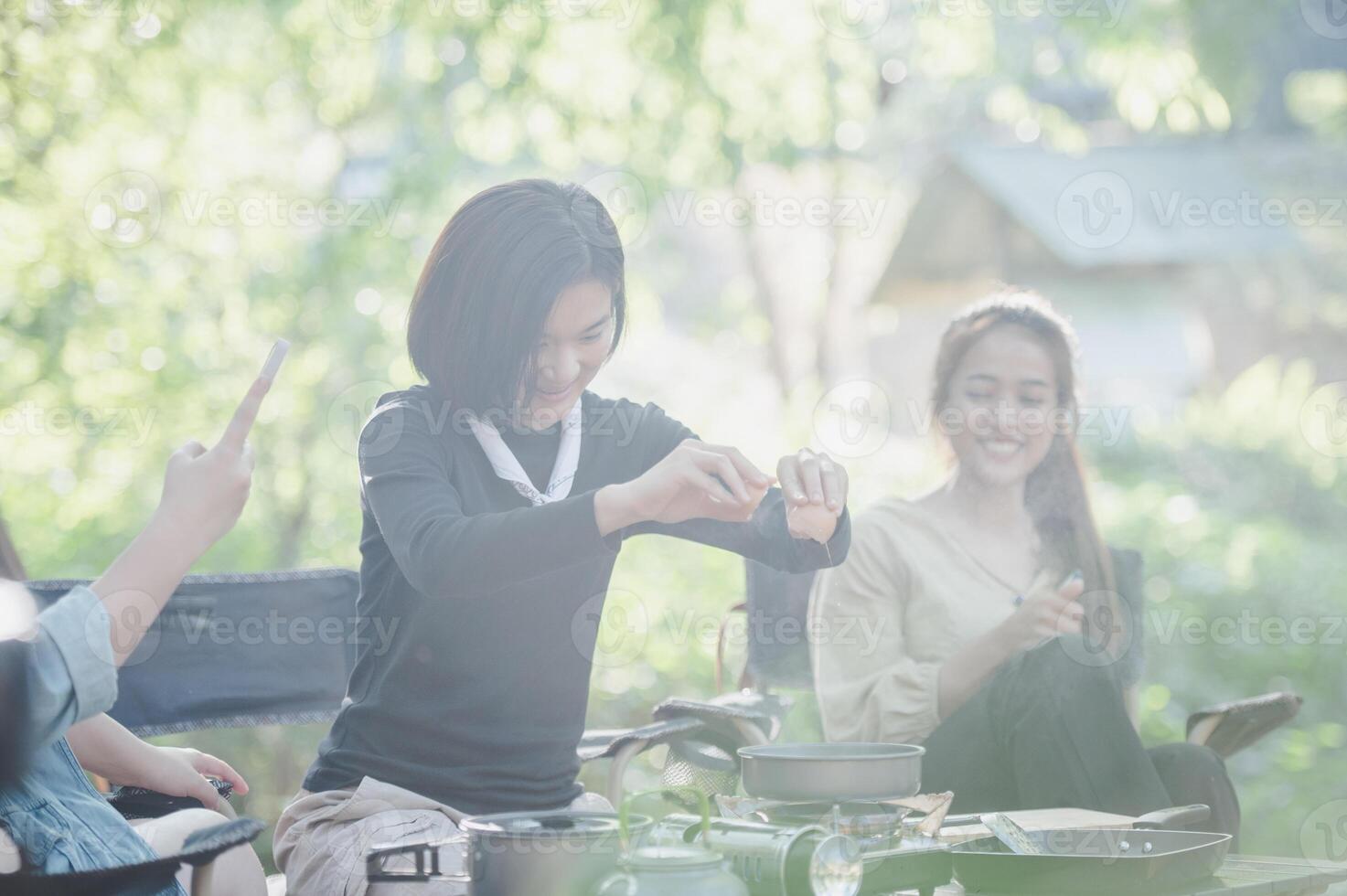 Young women cooking and use smartphone take photo on camping