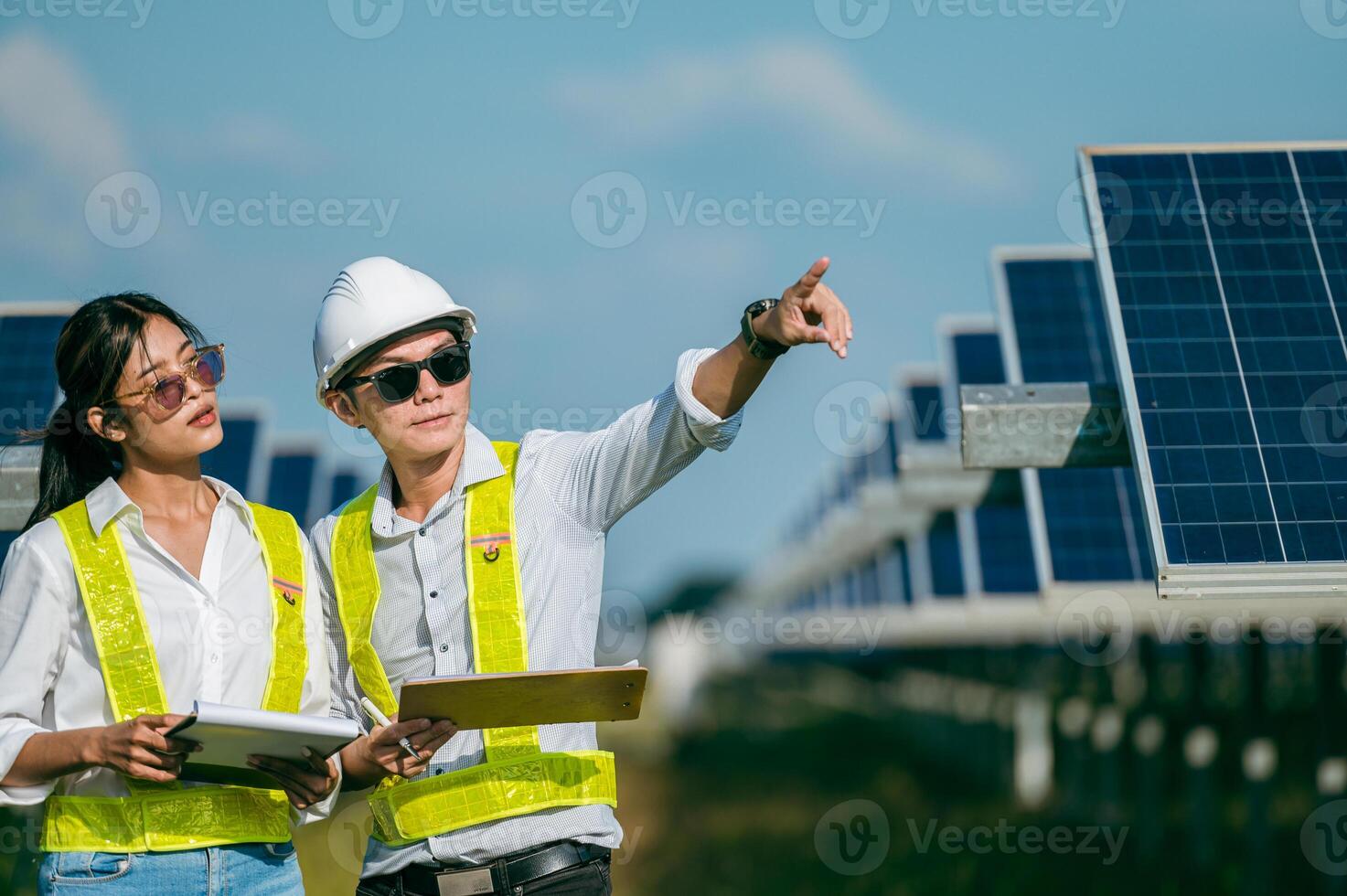 joven inspector asiático ingeniero hombre y mujer caminando comprobando la operación en una granja solar foto