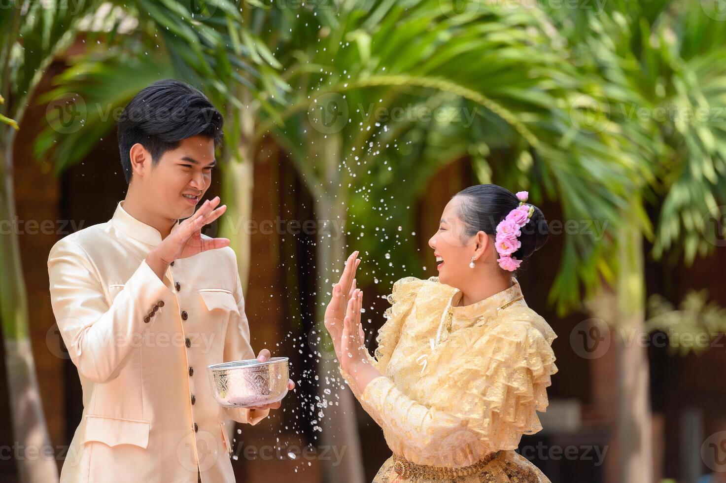 Young couple splashing water from bowl on Songkran festival photo