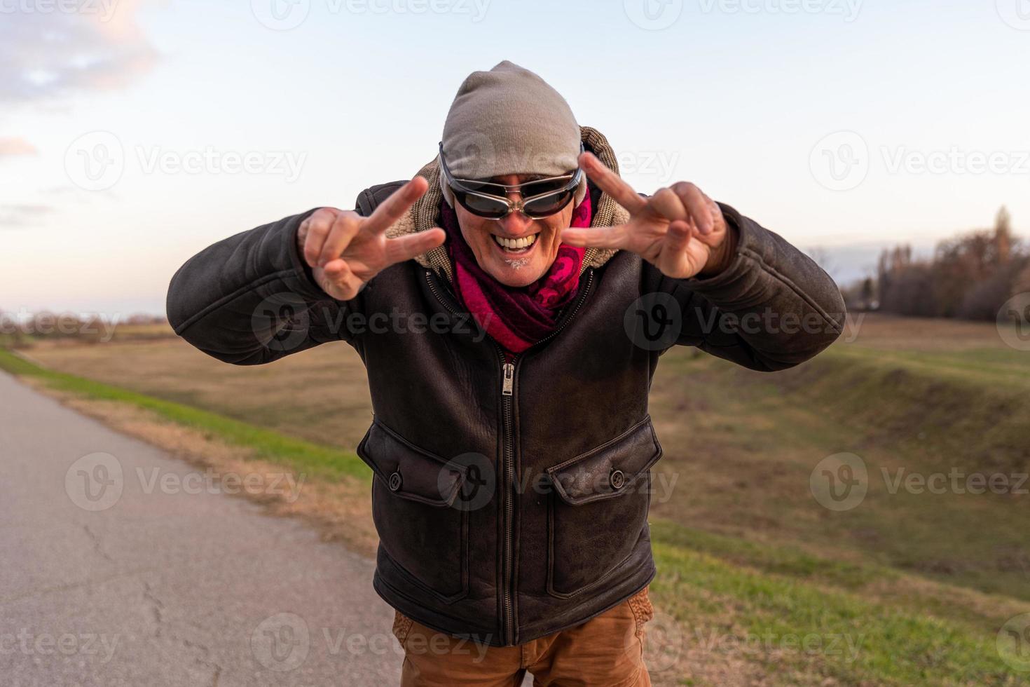 middle aged man wearing winter clothes have fun and making victory sign with hands outdoors photo