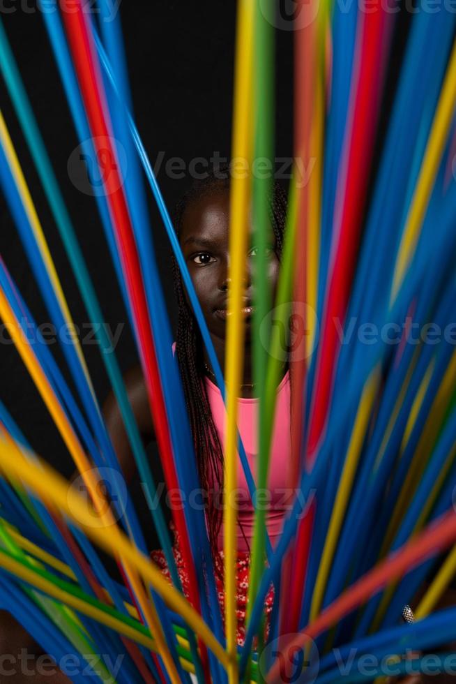 retrato de joven bonito africano adolescente soportes detrás largo de colores pajitas foto