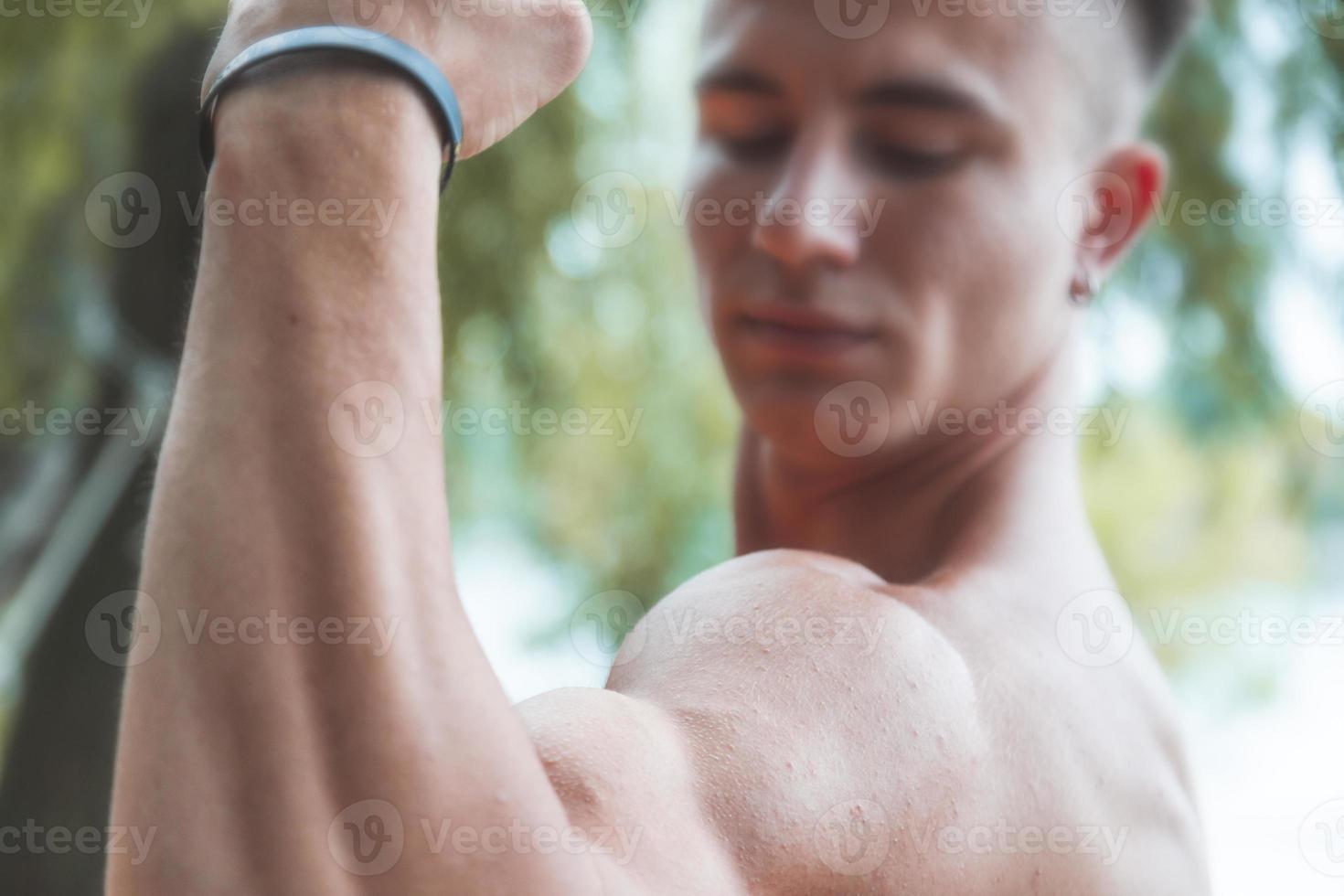 young muscular adult showing off his biceps outdoors photo