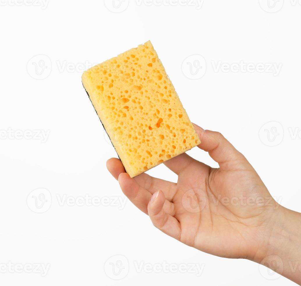 female hand holds a yellow kitchen sponge for washing dishes photo