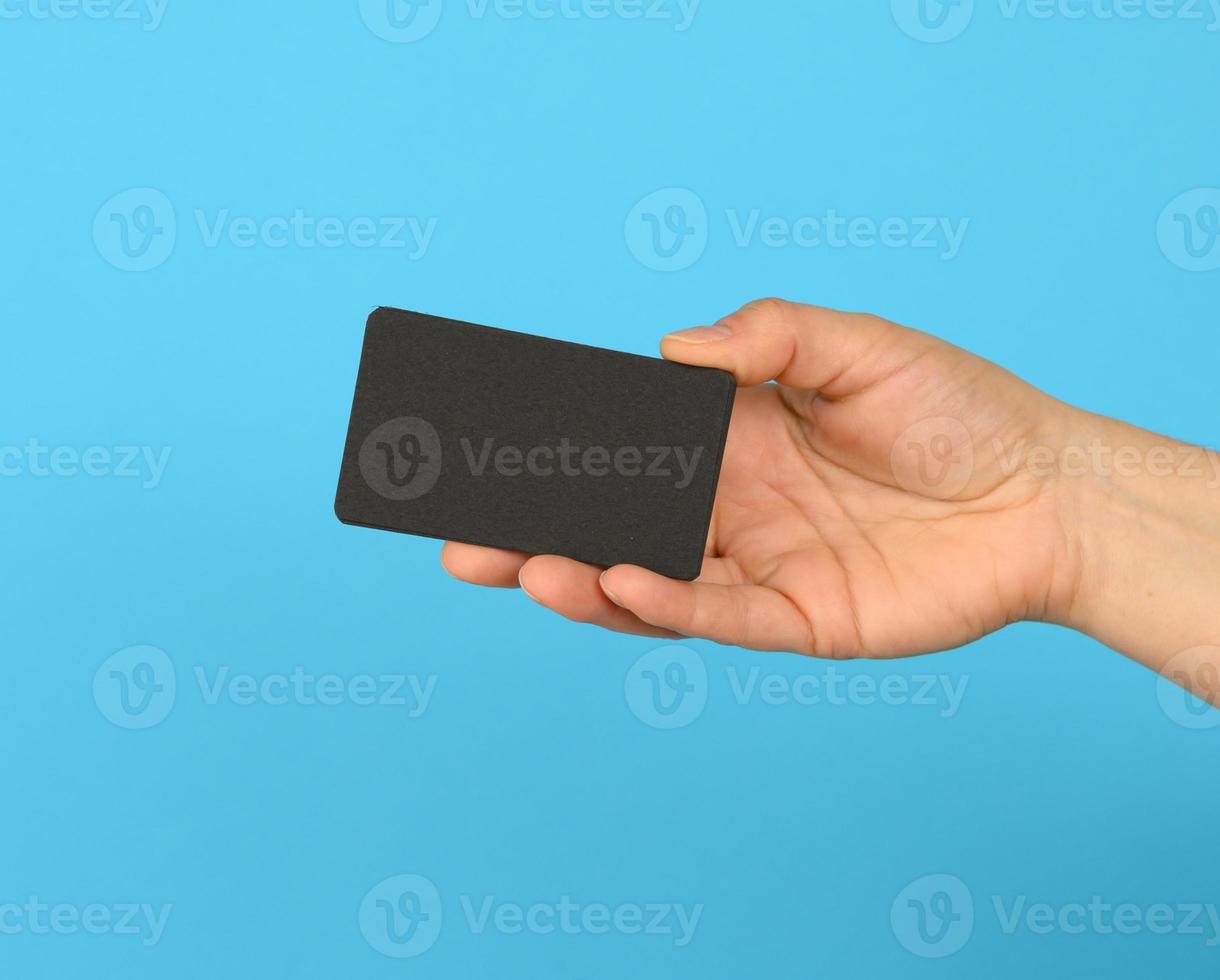 female hand holding a stack of blank black business cards photo