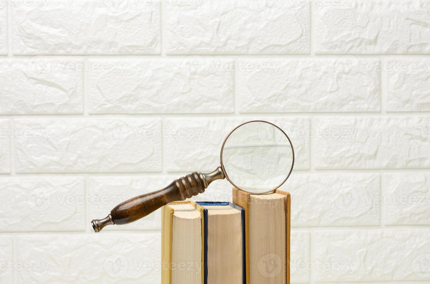 a wooden magnifying glass lies on a stack of books, new knowledge and discoveries are reading books photo