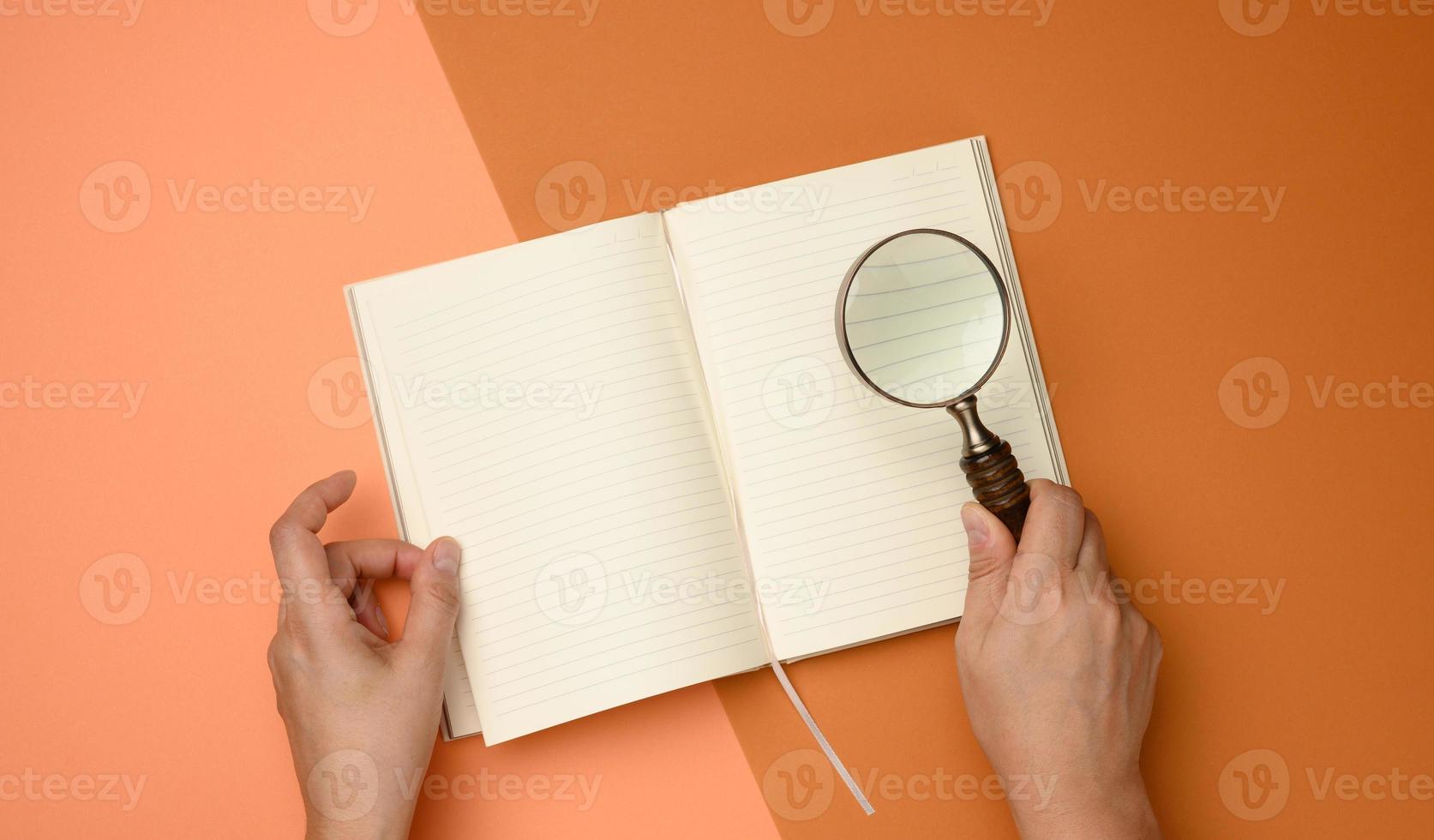 open paper notebook with blank white sheets and a wooden magnifier on a orange background photo