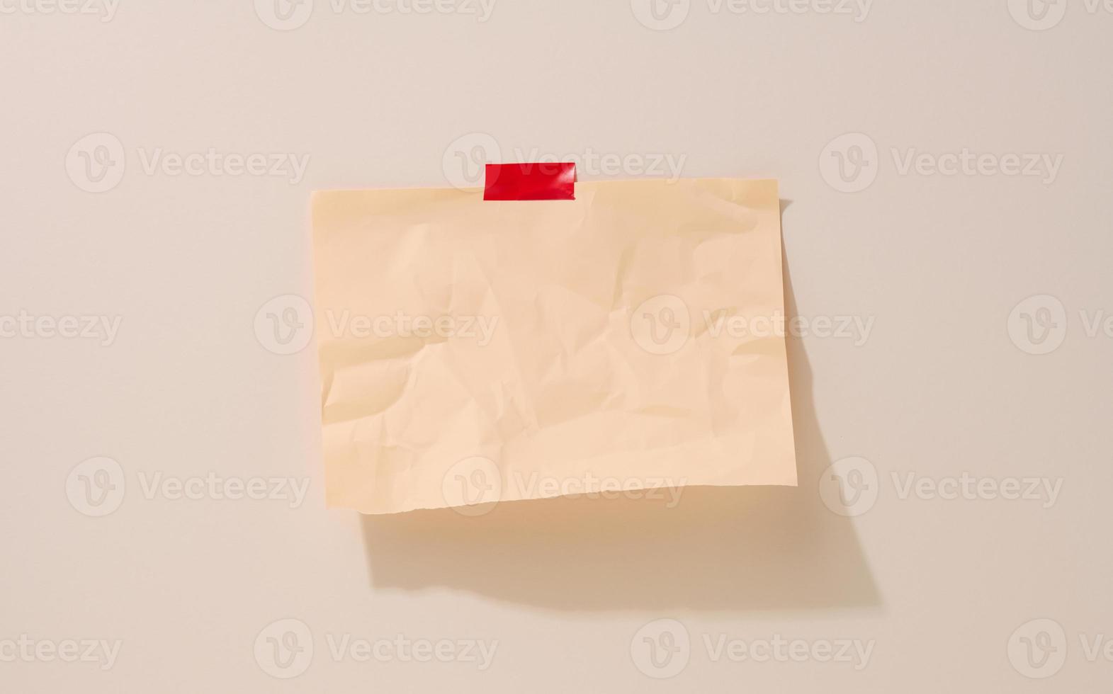 blank rectangular crumpled beige sheet of paper glued on a light beige background. Place for an inscription, announcement photo