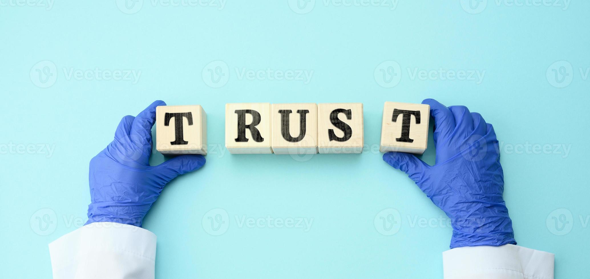 wooden blocks with the inscription trust in the hands of the doctor on a blue background, trust in the doctor and the medical system photo