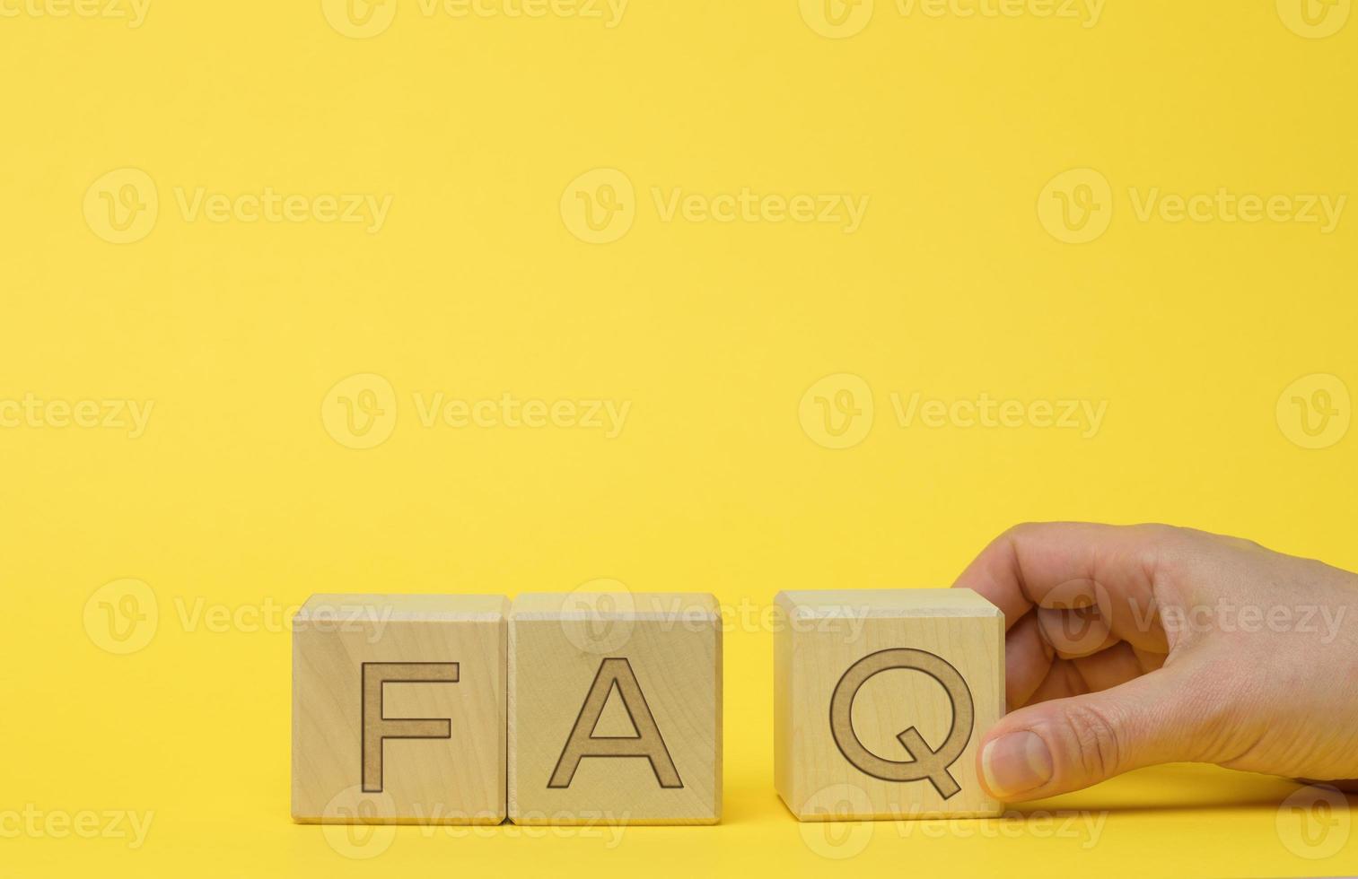 inscription FAQ frequently asked questions on wooden blocks on a yellow background photo