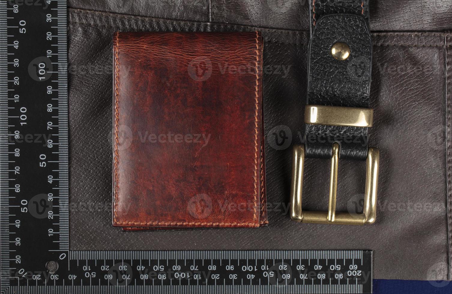 Leather goods purse and belt against the background of a ruler for cutting and sewing. photo