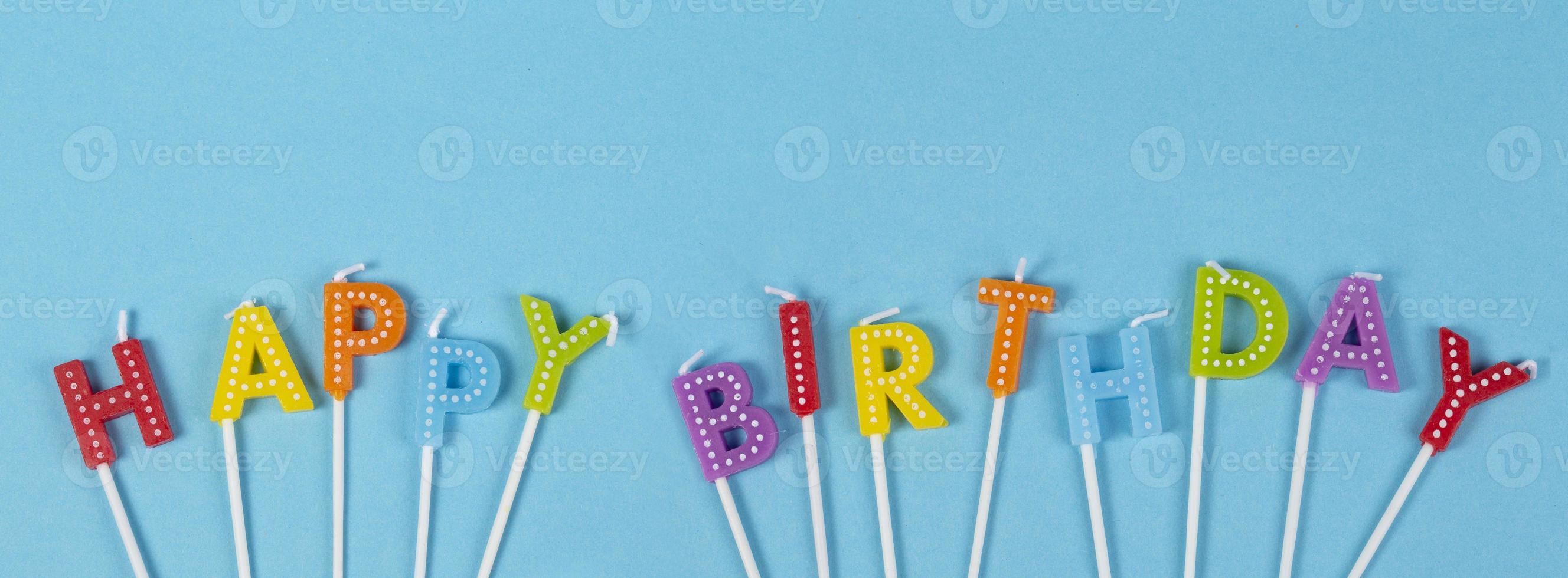 Colorful candles in letters with Happy Birthday lettering isolated on blue narrow background photo