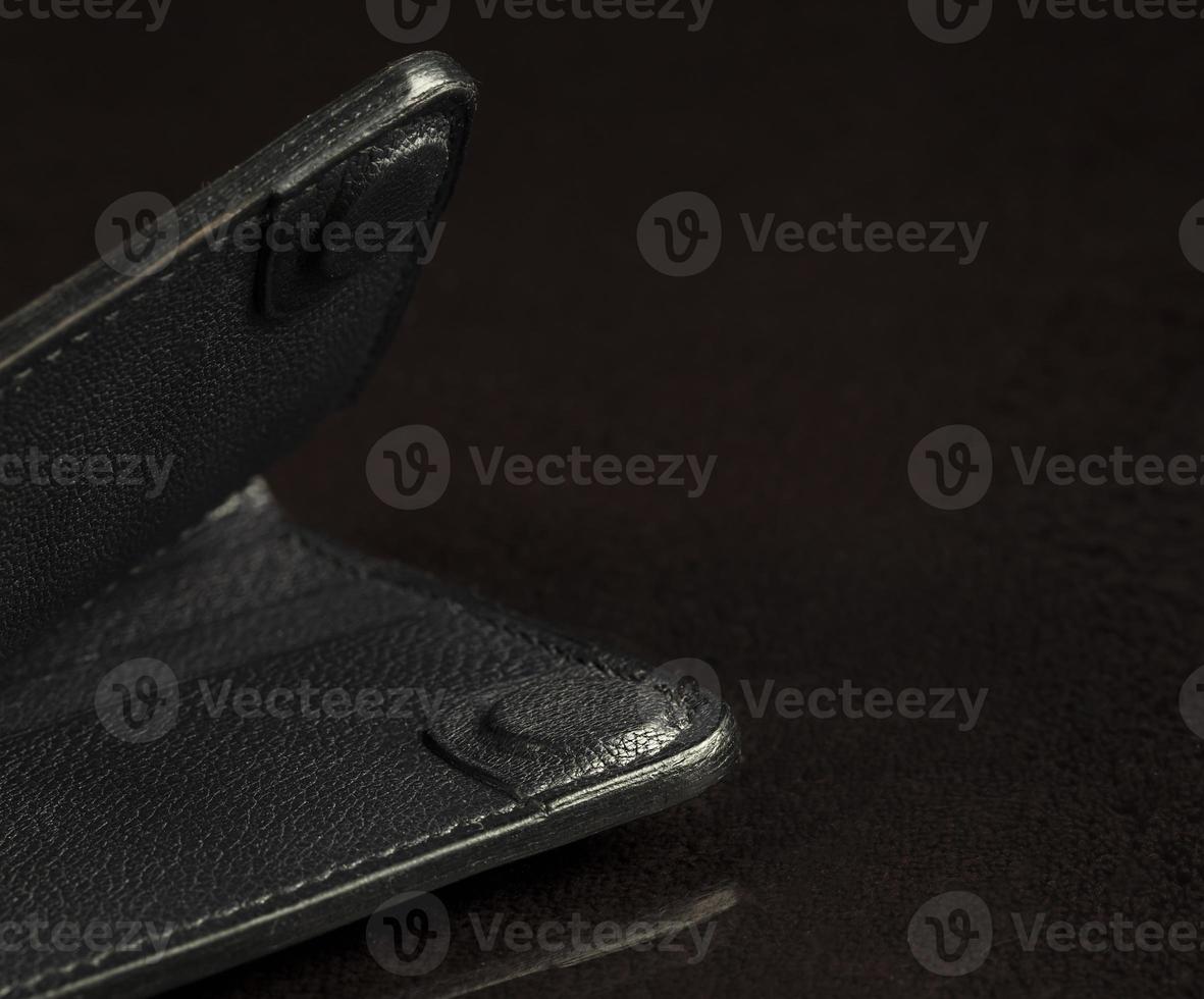Part of a black leather wallet on a black background. photo