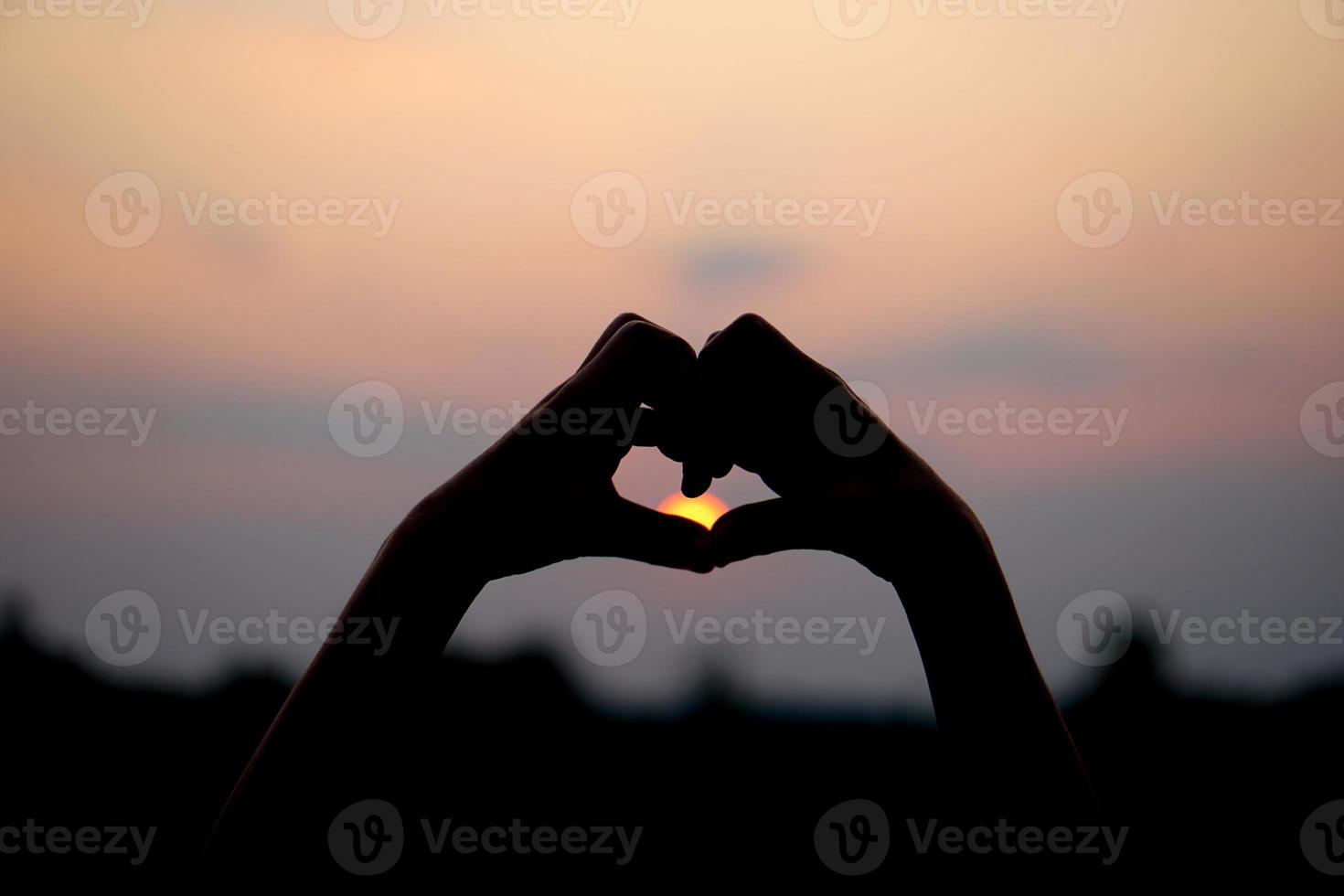 heart shaped human hand silhouette sunset background photo