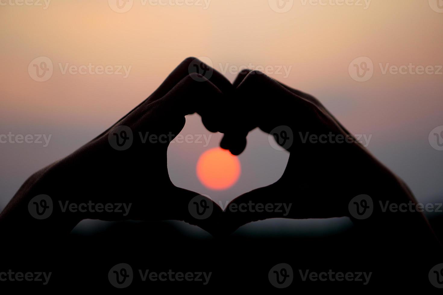 heart shaped human hand silhouette sunset background photo