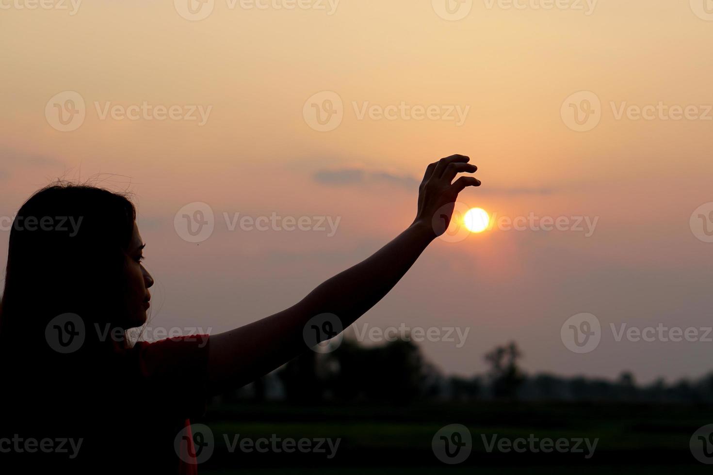 silhouette of human hand raised to make a wish, sunset background photo