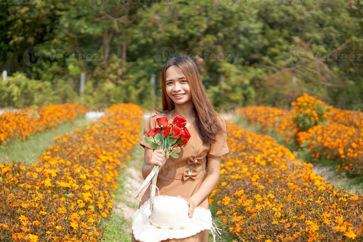 asiático mujer sonriente felizmente entre hermosa flores foto