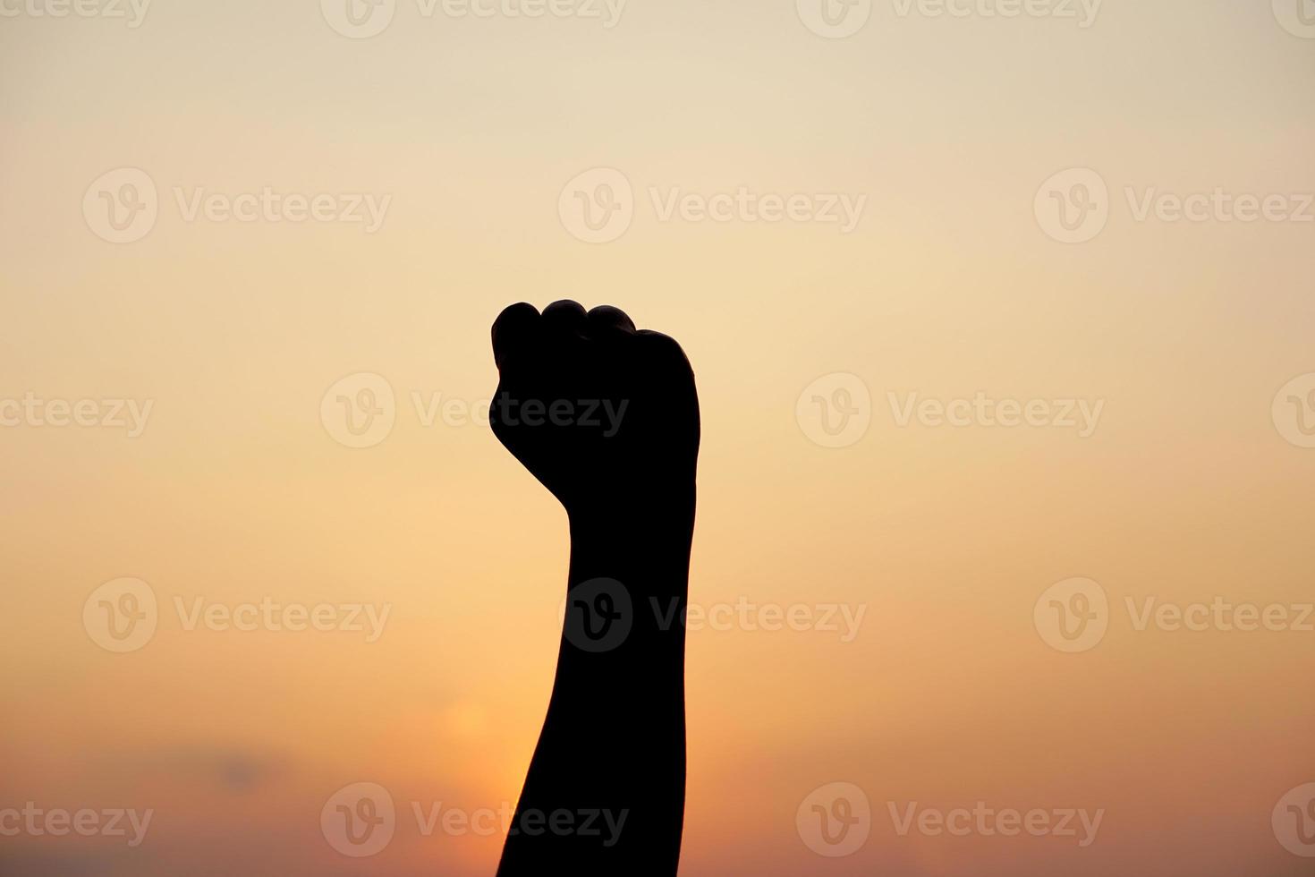 silueta de humano mano elevado a hacer un desear, puesta de sol antecedentes foto