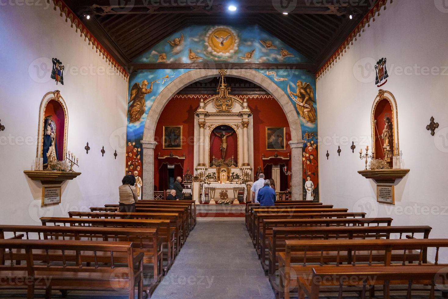 Walkway between wooden pews leading towards crucifix in church photo