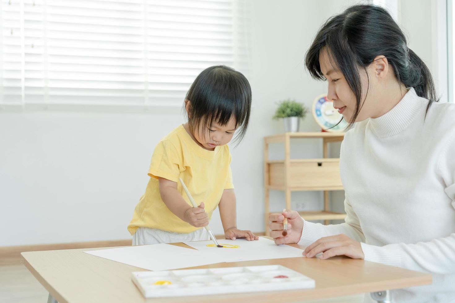 contento Asia madre aprendizaje pintar para pequeño muchacha. familia es contento y emocionado en el casa. madre y hija teniendo divertido gasto hora juntos. día festivo, actividad, ejecutivo función, iq, eq foto