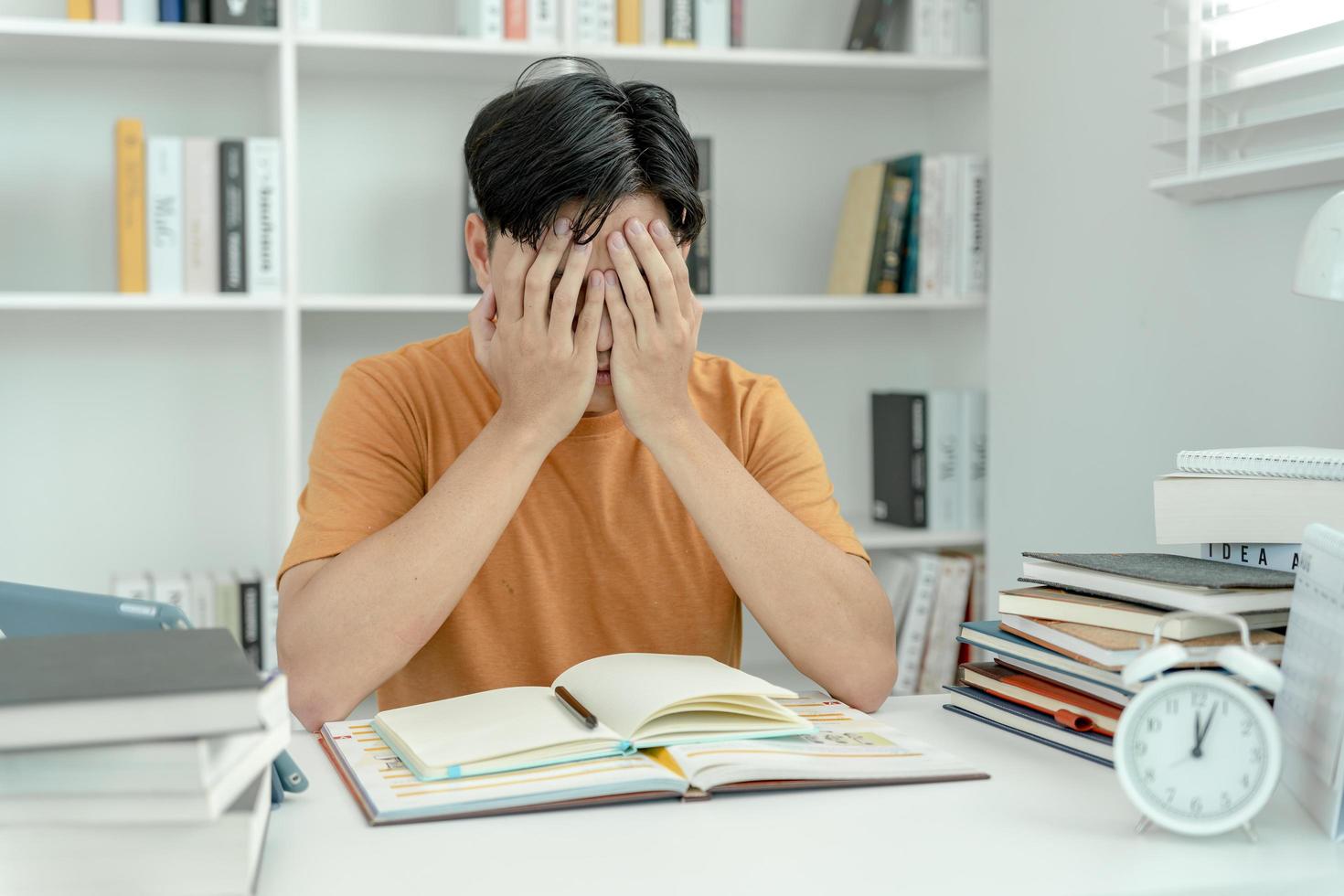 Asian student man have anxiety because of exams, male prepare for test and learning lessons in the library. stress, despair, haste, misunderstanding reading, discouraged, expectation, knowledge, tired photo