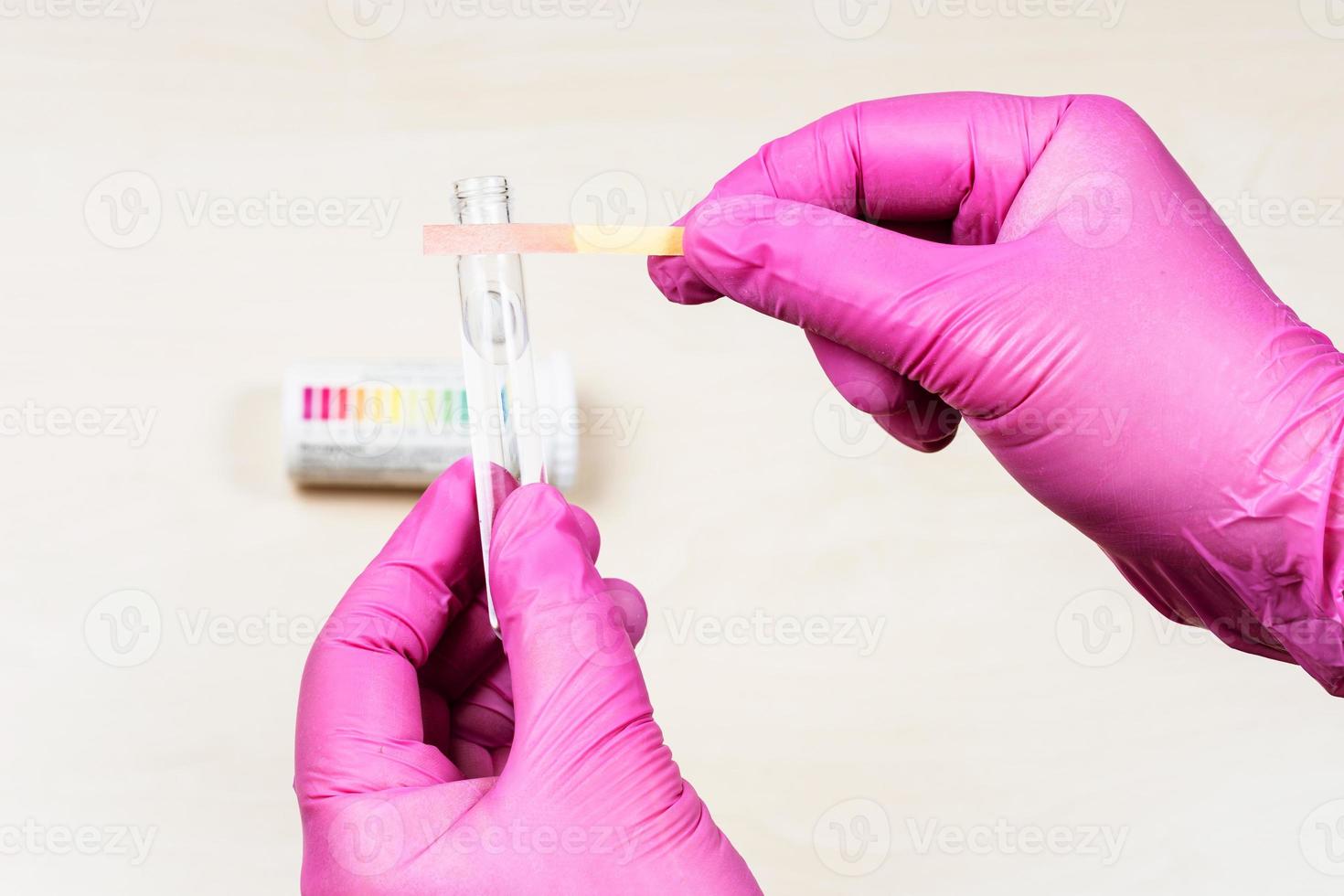 hands holding pink acid litmus paper and test tube photo