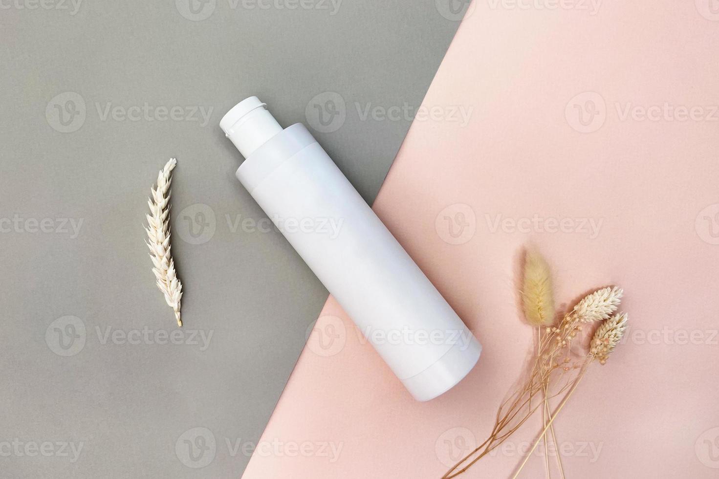 top view of white plastic bottle on gray and pink photo