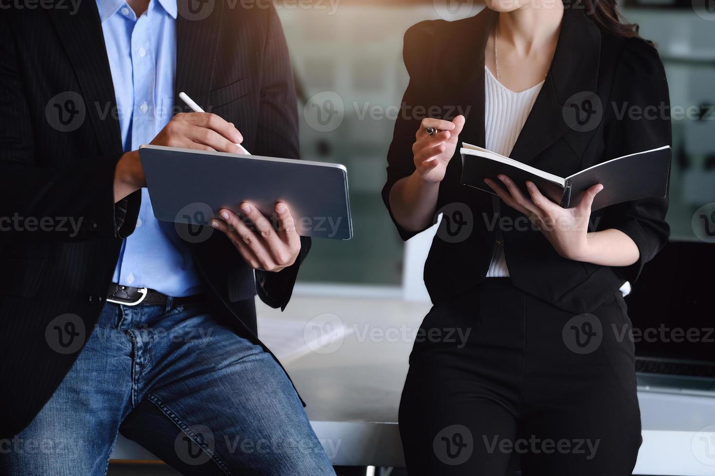 en la consulta, un asesor masculino usa un bolígrafo para señalar una tableta para explicar la reestructuración de ganancias a las propietarias de empresas. foto