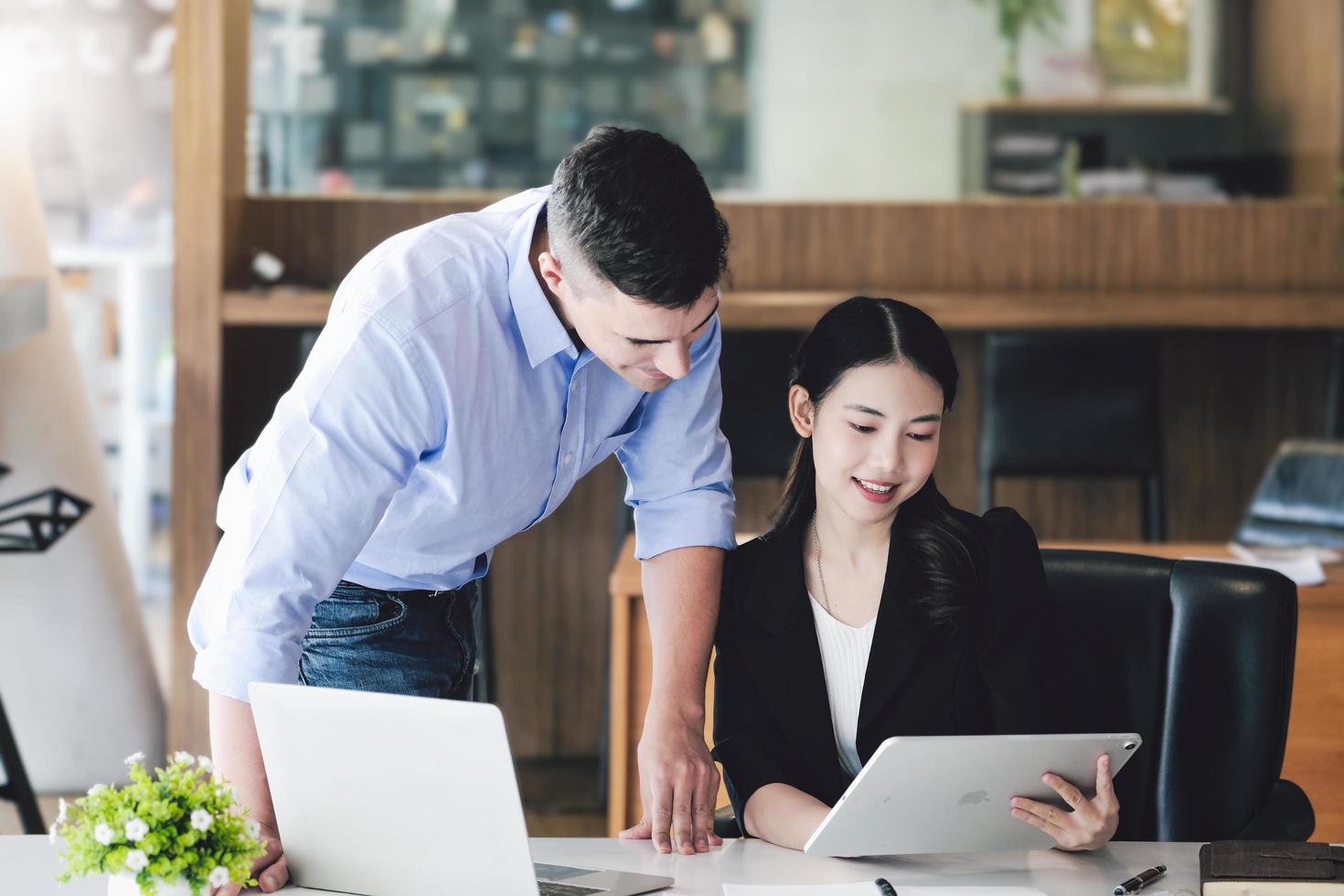 el gerente de marketing masculino expresó su satisfacción por vender los productos de la empresa. donde los miembros del equipo muestran las ventas desde la pantalla de su ipad. foto