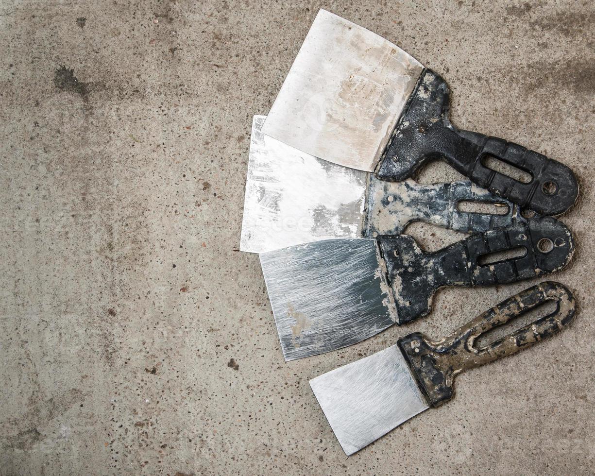 Dirty spatulas on concrete floor photo