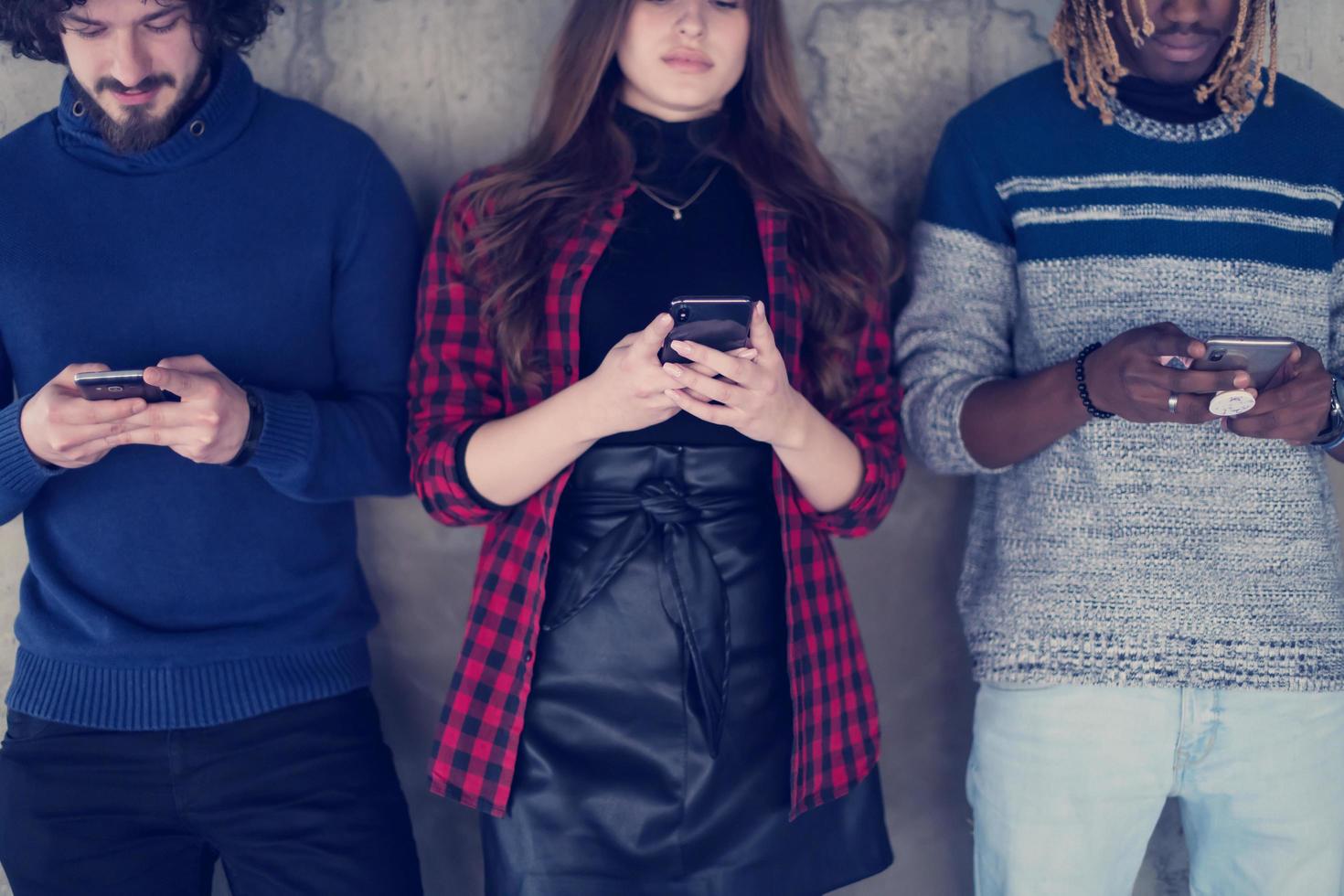 casual multiethnic business team using mobile phones in front of a concrete wall photo