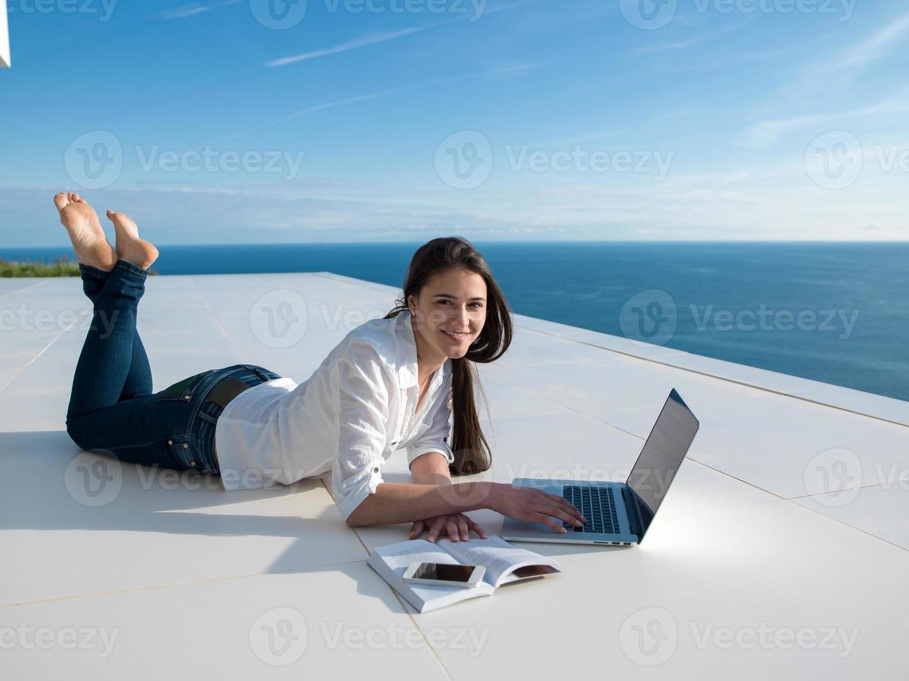 relaxed young woman at home working on laptop photo