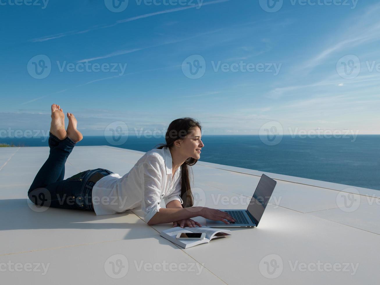 relaxed young woman at home working on laptop photo