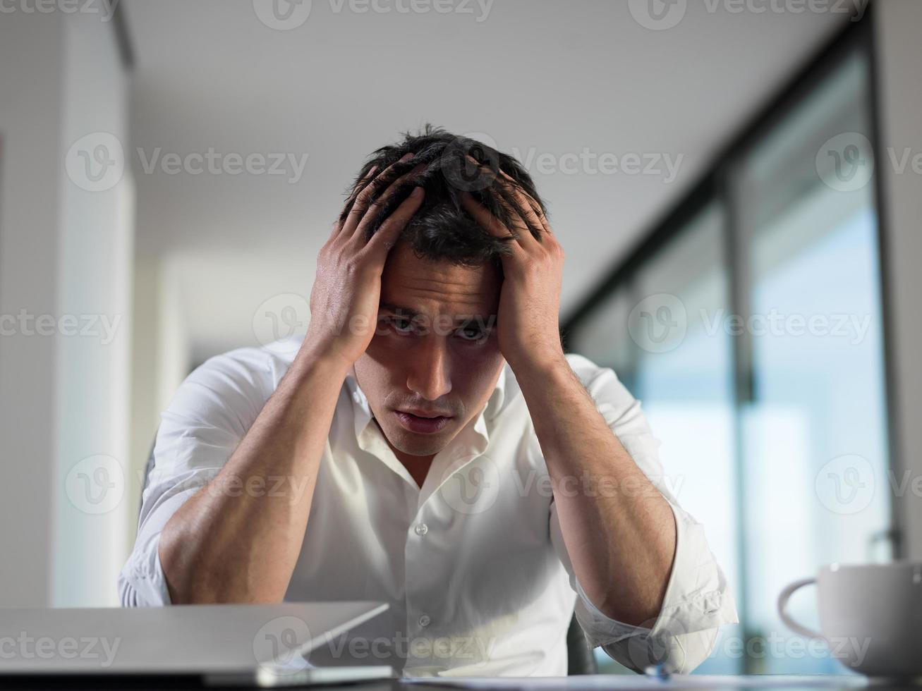 joven hombre de negocios frustrado que trabaja en una computadora portátil en casa foto
