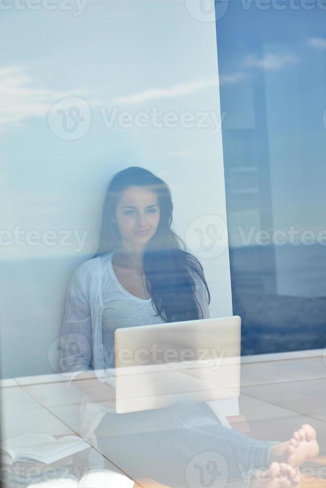 relaxed young woman at home working on laptop computer photo