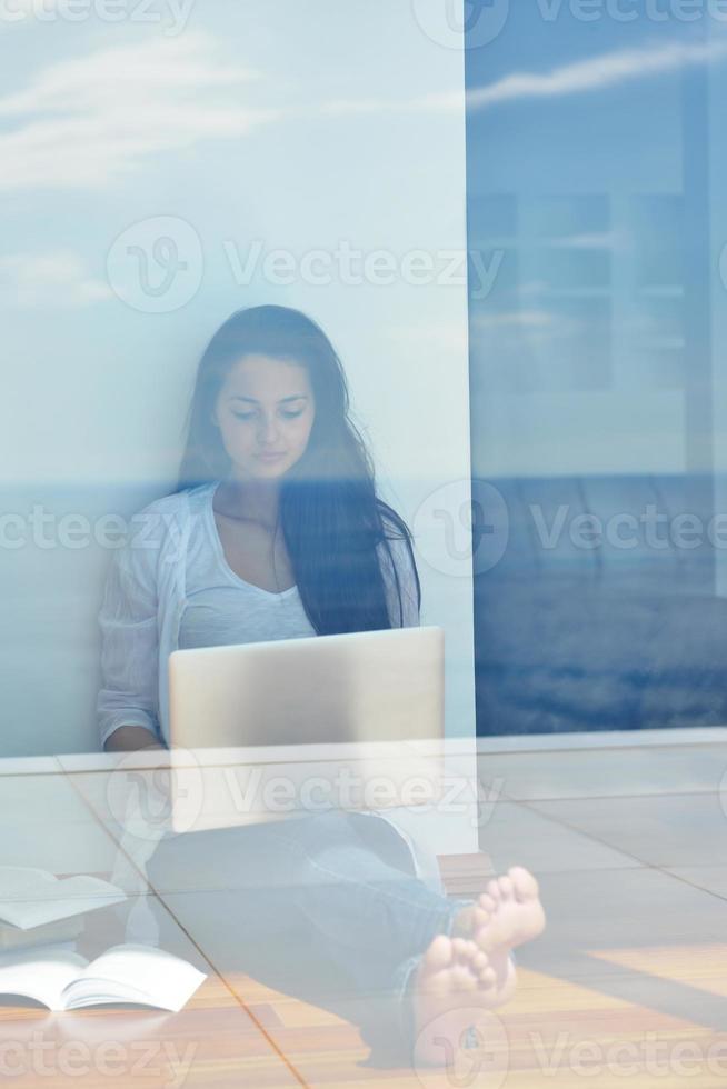 relaxed young woman at home working on laptop computer photo